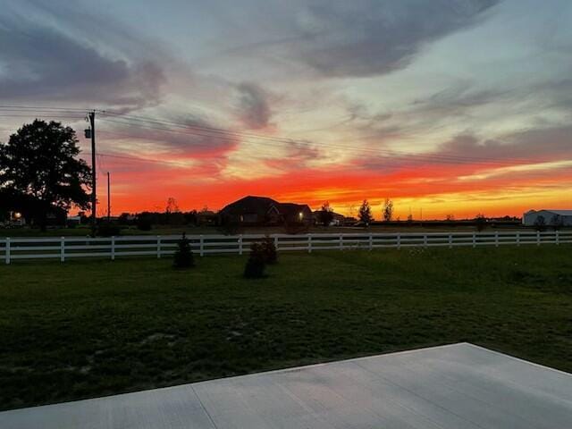 yard at dusk featuring a rural view