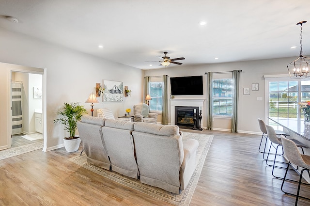 living room featuring ceiling fan with notable chandelier, light hardwood / wood-style flooring, and a wealth of natural light