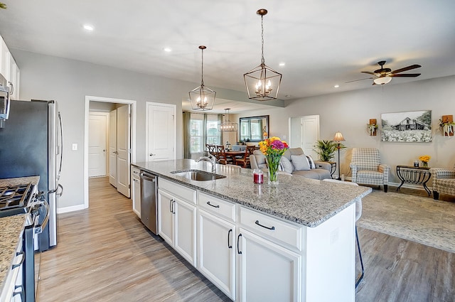 kitchen with sink, white cabinetry, hanging light fixtures, a center island with sink, and appliances with stainless steel finishes