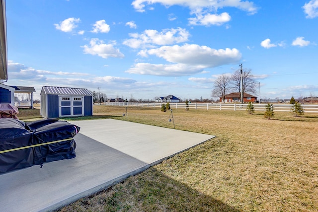 view of yard featuring a rural view, a storage shed, and a patio area