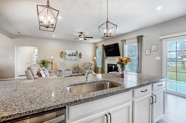 kitchen featuring white cabinetry, sink, stainless steel dishwasher, and stone countertops