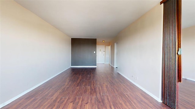 unfurnished room with dark wood finished floors and baseboards