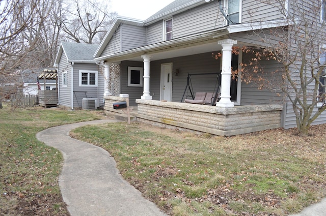 view of front of property featuring covered porch, roof with shingles, a front lawn, and central air condition unit