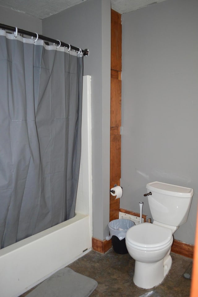 bathroom with stone finish flooring, shower / bath combo with shower curtain, and toilet