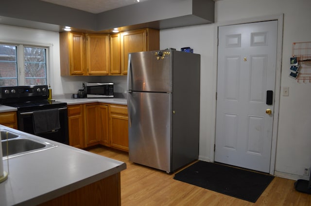 kitchen with light wood-type flooring, brown cabinetry, stainless steel appliances, and light countertops