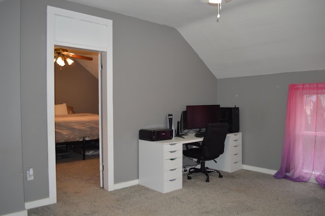 carpeted office space featuring a ceiling fan, vaulted ceiling, and baseboards