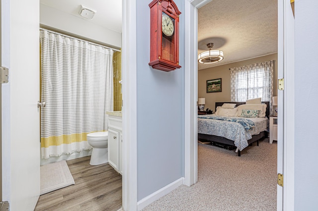 full bath featuring a textured ceiling, connected bathroom, baseboards, toilet, and a shower with shower curtain