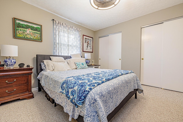 bedroom featuring a textured ceiling, carpet floors, and multiple closets
