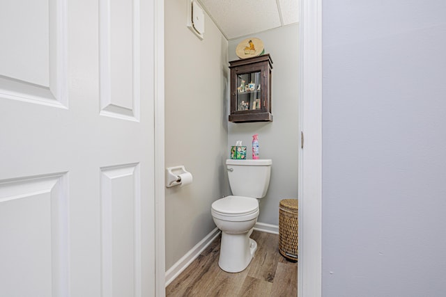 bathroom featuring baseboards, wood finished floors, and toilet