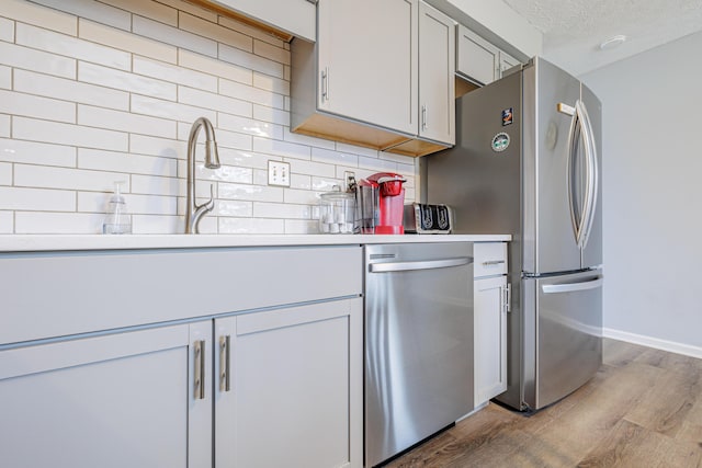 kitchen with wood finished floors, appliances with stainless steel finishes, and tasteful backsplash