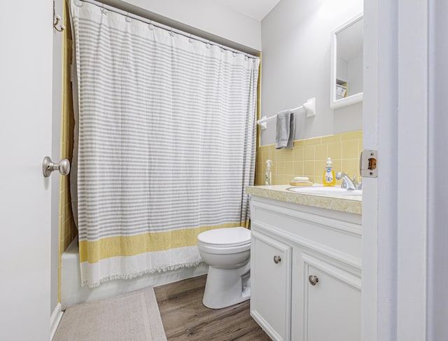 full bath featuring wood finished floors, vanity, shower / tub combo with curtain, tile walls, and toilet