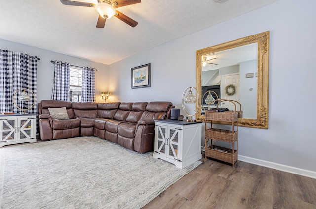 living area with ceiling fan, baseboards, wood finished floors, and a textured ceiling