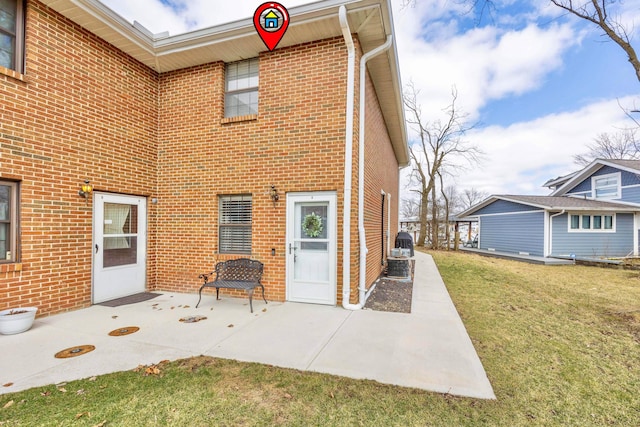 back of property featuring brick siding, a yard, a patio area, and central AC unit