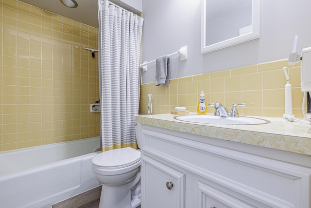 bathroom featuring tile walls, shower / bath combo with shower curtain, toilet, and vanity