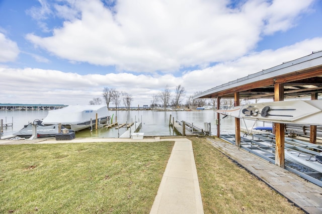 dock area with a yard, boat lift, and a water view