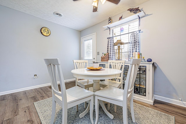 dining room featuring a textured ceiling, wood finished floors, visible vents, and ceiling fan