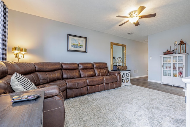 living room with baseboards, a ceiling fan, wood finished floors, and a textured ceiling