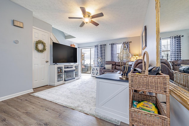 living area with plenty of natural light, a ceiling fan, wood finished floors, and a textured ceiling