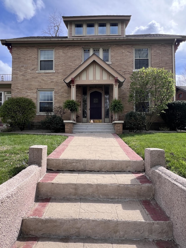 american foursquare style home with a front lawn and brick siding