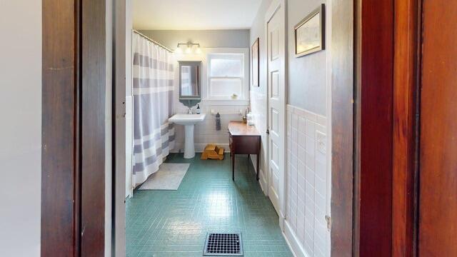 full bathroom with a shower with curtain, a sink, and visible vents