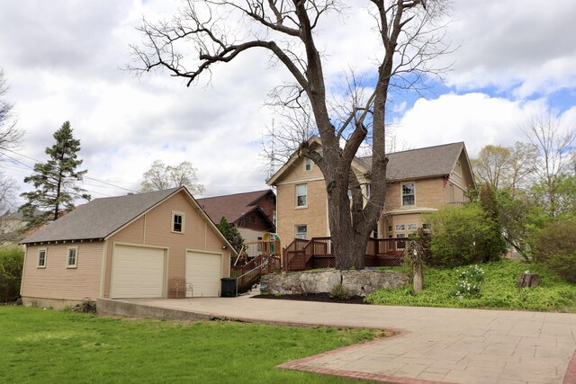 view of front of house with a garage, an outbuilding, a front lawn, and a deck