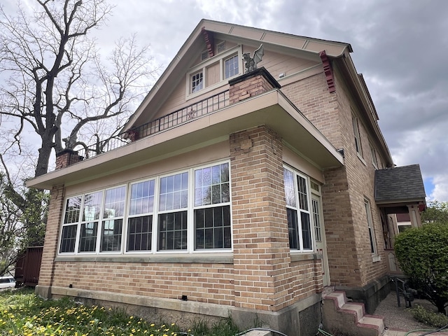 view of side of home with a chimney and brick siding