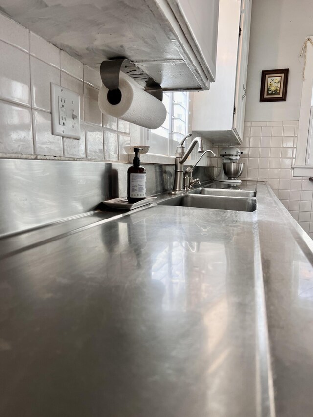details featuring stainless steel countertops, backsplash, white cabinetry, and a sink