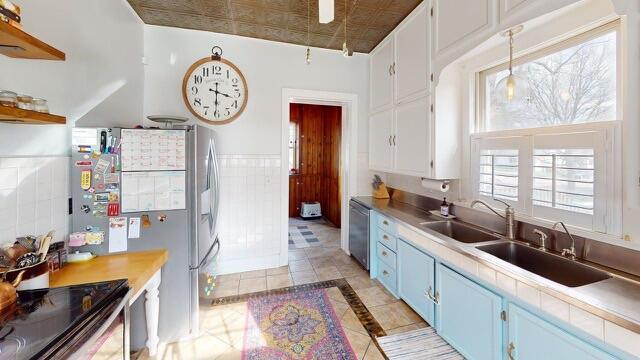 kitchen featuring blue cabinets, light tile patterned floors, white cabinetry, light countertops, and appliances with stainless steel finishes