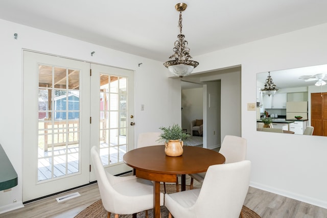 dining space featuring light wood finished floors, plenty of natural light, and visible vents