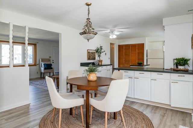 dining room featuring light wood-style flooring, baseboards, and ceiling fan