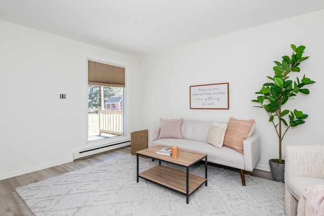 living area featuring a baseboard heating unit, baseboards, and light wood finished floors