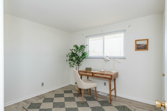 home office with light wood-style flooring and baseboards