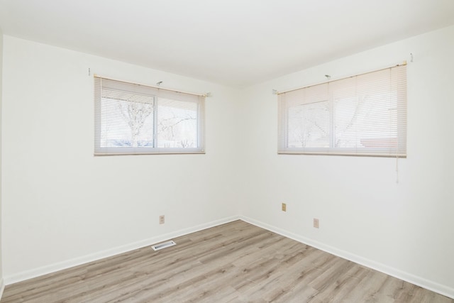 spare room featuring visible vents, baseboards, and light wood-style floors