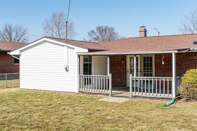 back of property with a lawn, fence, a shingled roof, brick siding, and a chimney