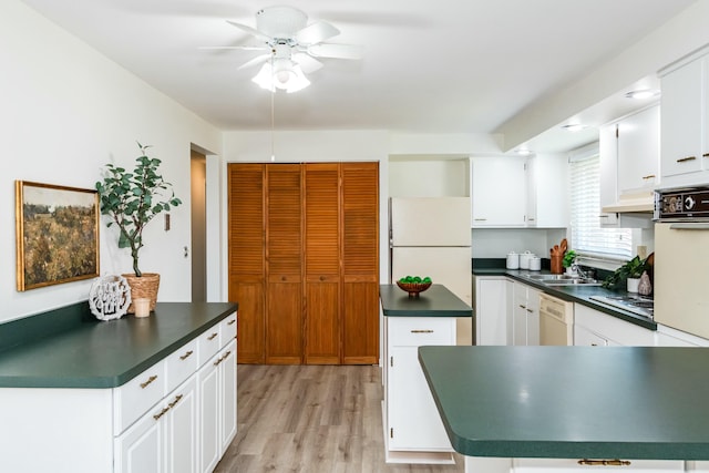 kitchen with a sink, dark countertops, white cabinetry, white appliances, and light wood finished floors