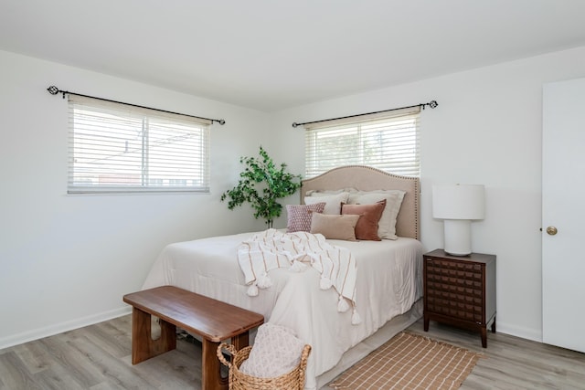 bedroom with multiple windows, light wood-style flooring, and baseboards