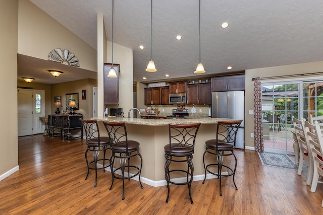 725 Loxley Ln, Troy, OH 45373 - kitchen with stainless steel appliances, a breakfast bar area, wood finished floors, dark brown cabinets, and healthy amount of natural light