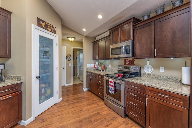 725 Loxley Ln, Troy, OH 45373 - kitchen featuring appliances with stainless steel finishes, light wood-style floors, baseboards, vaulted ceiling, and light stone counters