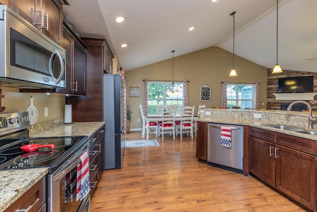 725 Loxley Ln, Troy, OH 45373 - kitchen with appliances with stainless steel finishes, a sink, light wood-style floors, decorative light fixtures, and vaulted ceiling