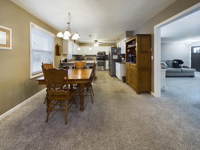 dining area with ceiling fan with notable chandelier and light carpet