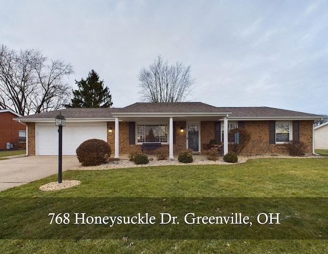 single story home with a porch, a garage, and a front lawn