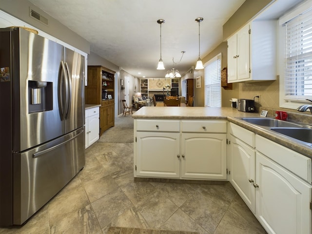 kitchen featuring stainless steel refrigerator with ice dispenser, sink, hanging light fixtures, kitchen peninsula, and a wealth of natural light