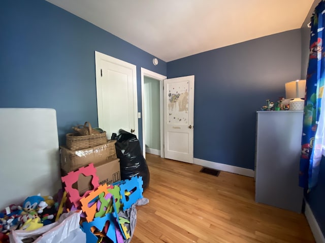 recreation room featuring visible vents, baseboards, and wood finished floors