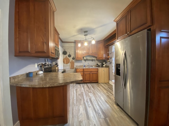 kitchen featuring a sink, brown cabinetry, stainless steel appliances, a peninsula, and light wood-type flooring