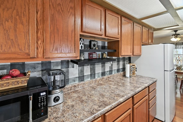 11372 Kickapoo Path, Lakeview, OH 43331 - kitchen featuring black microwave, freestanding refrigerator, decorative backsplash, ceiling fan, and brown cabinetry