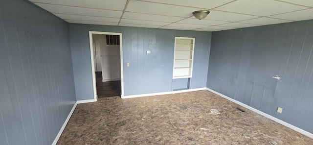 spare room featuring a drop ceiling and baseboards