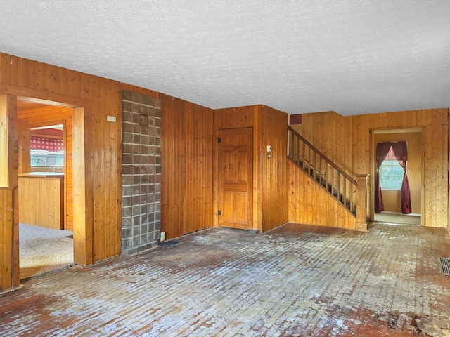 interior space featuring wood walls, visible vents, stairway, and a textured ceiling