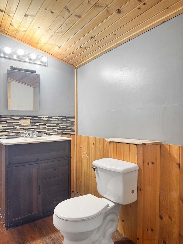 half bathroom with lofted ceiling, toilet, wood ceiling, vanity, and wood finished floors