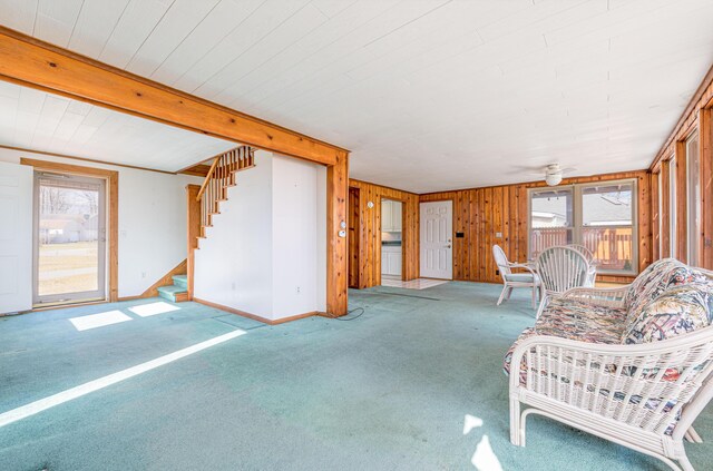 10989 Seminole Shore Dr, Huntsville, OH 43324 - carpeted living room featuring stairway, ceiling fan, wood walls, beamed ceiling, and baseboards