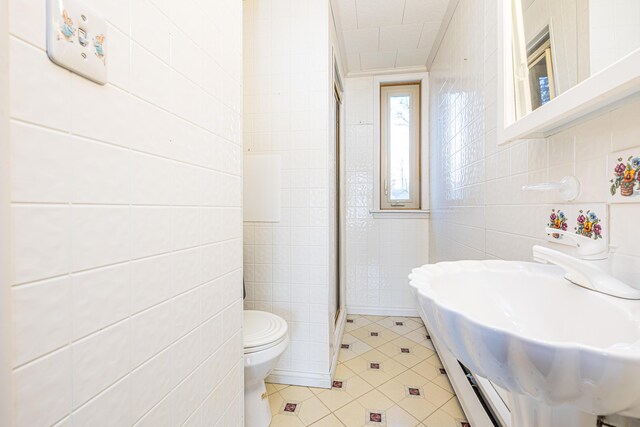 10989 Seminole Shore Dr, Huntsville, OH 43324 - full bathroom with tile walls, toilet, a shower stall, tile patterned flooring, and a sink
